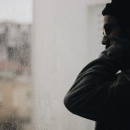 Man looking at rain outside of window