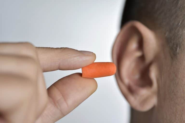 man putting earplugs into his ear.