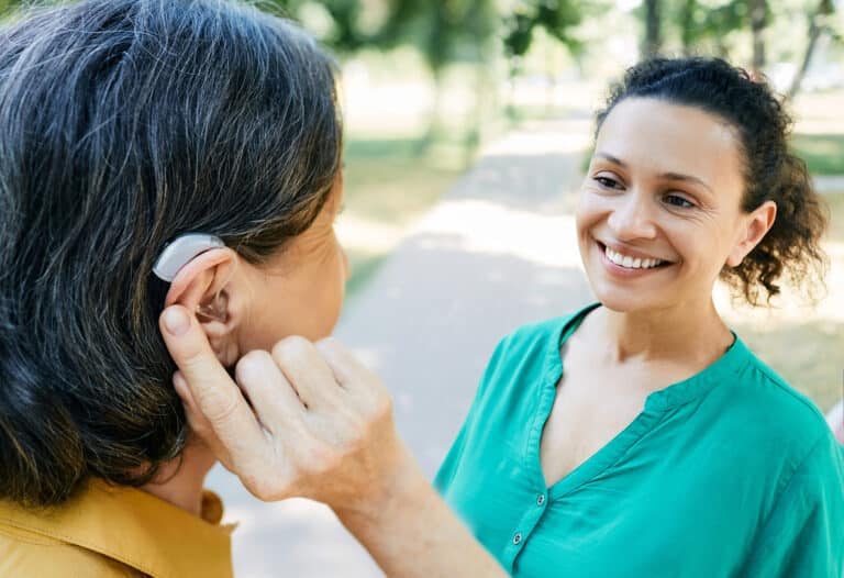Woman with hearing aid talking with her friend outside.