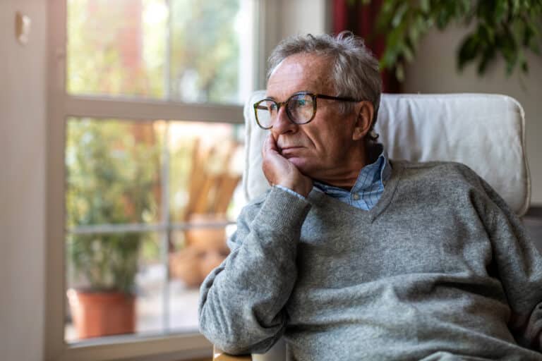 Older man looking out his window.