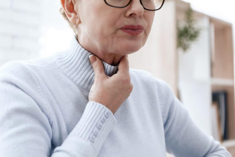 Woman holds neck while swallowing