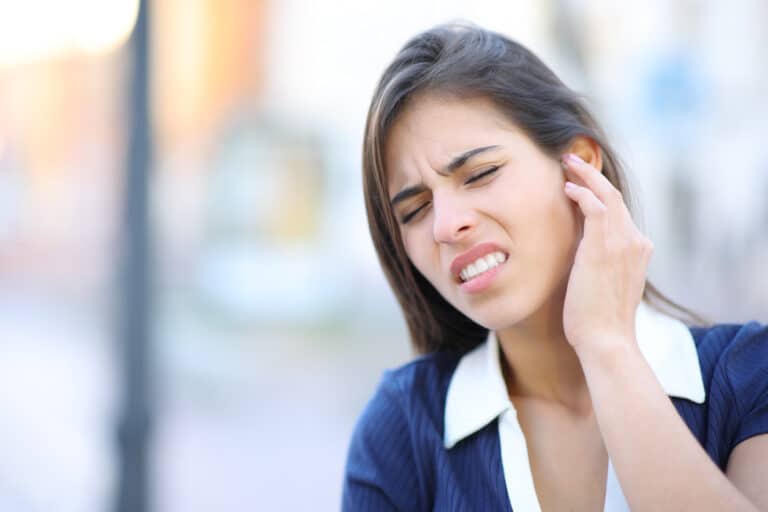 Woman holding her ear and frowning