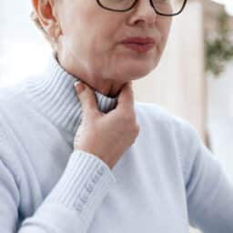 Woman holding her sore throat